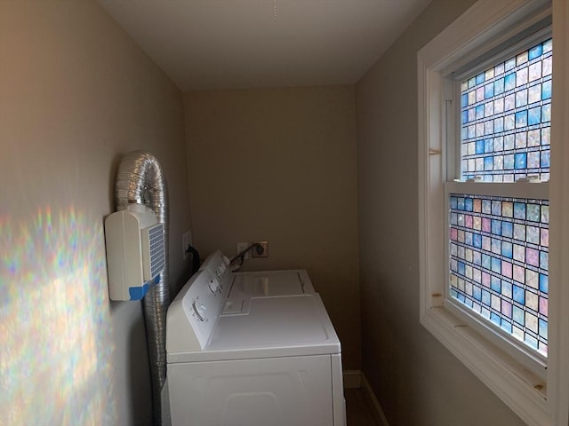 washroom with washing machine and dryer, healthy amount of natural light, and baseboards