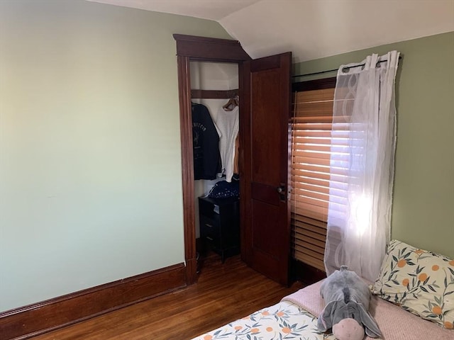 bedroom featuring dark wood-style floors, a closet, and lofted ceiling