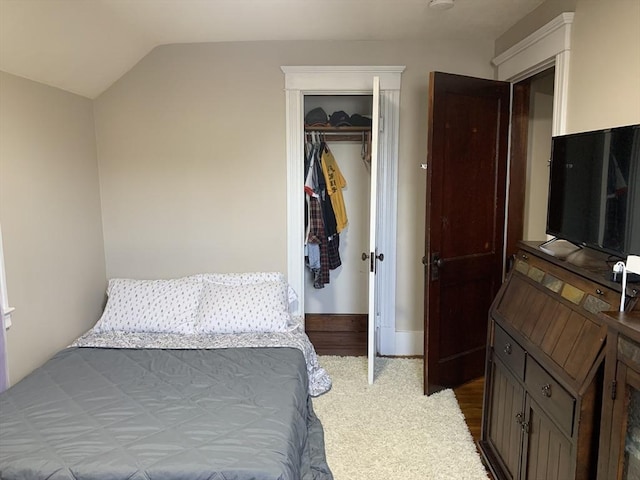 carpeted bedroom with vaulted ceiling and a closet