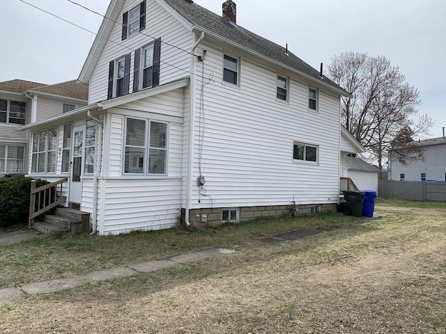 view of side of property with a chimney and roof with shingles