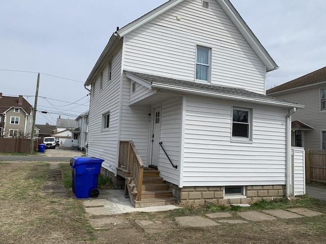 rear view of property with fence and roof with shingles
