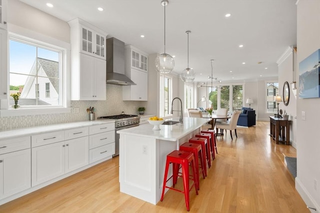 68 Summer St Unit B, Natick, MA 01760 - kitchen with wall chimney range hood, high end stainless steel range oven, a sink, light wood finished floors, and an island with sink