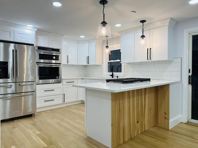 kitchen featuring stainless steel appliances, light wood-style floors, light countertops, and white cabinets