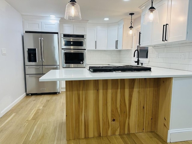 kitchen with stainless steel appliances, white cabinetry, backsplash, and light wood finished floors