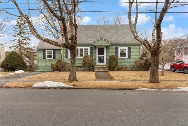 new england style home featuring entry steps and roof with shingles