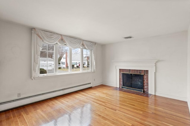 unfurnished living room with a brick fireplace, visible vents, baseboard heating, and wood finished floors