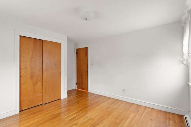 unfurnished bedroom featuring a closet, light wood-style flooring, and baseboards