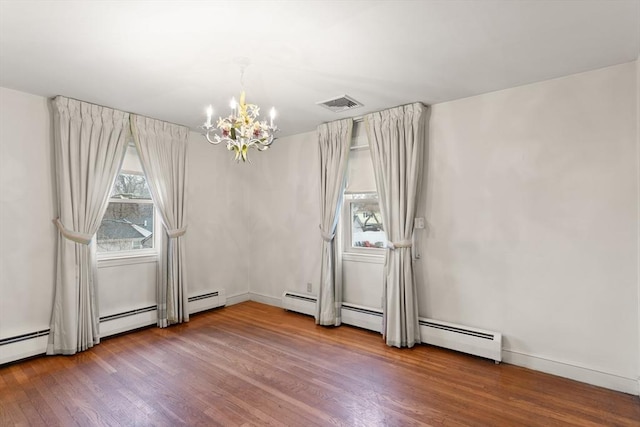 unfurnished room with a wealth of natural light, visible vents, a notable chandelier, and wood finished floors