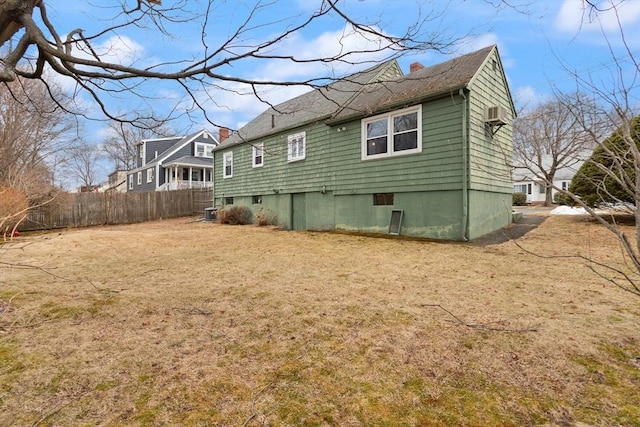 back of property with a chimney, fence, and a lawn