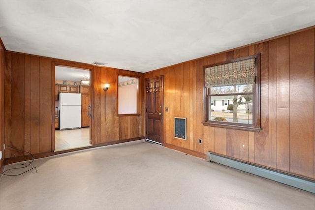 unfurnished room with a baseboard heating unit, visible vents, and wood walls