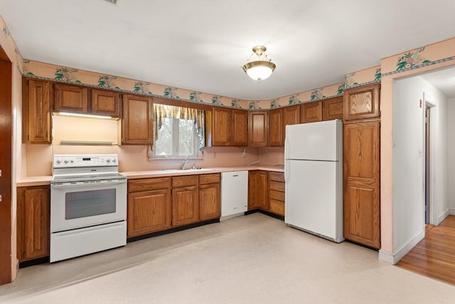 kitchen with white appliances, a sink, and brown cabinets