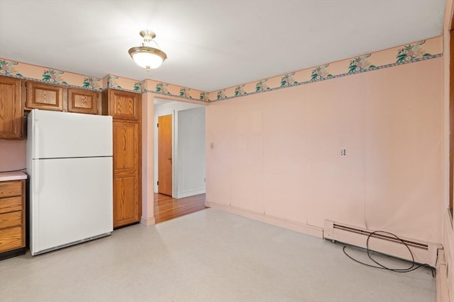 kitchen featuring a baseboard heating unit, brown cabinetry, light countertops, and freestanding refrigerator