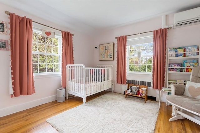 118 Academy Ave, Weymouth, MA 02188 - bedroom featuring a wall mounted air conditioner, wood finished floors, baseboards, and a nursery area