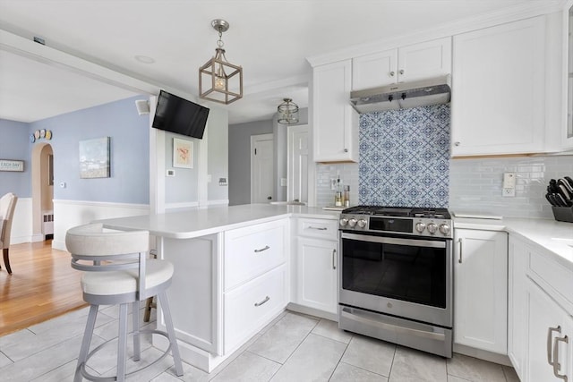 118 Academy Ave, Weymouth, MA 02188 - kitchen featuring stainless steel gas stove, under cabinet range hood, a peninsula, light countertops, and decorative backsplash