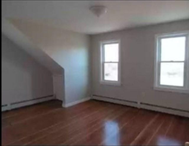 additional living space with baseboard heating and dark hardwood / wood-style floors