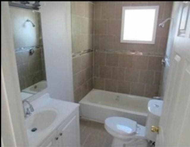 full bathroom featuring toilet, vanity, and tiled shower / bath