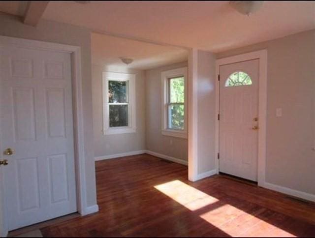 foyer with beamed ceiling and dark wood-type flooring