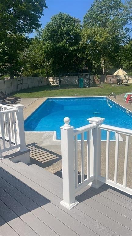 view of swimming pool featuring a wooden deck, a lawn, a fenced backyard, and a fenced in pool