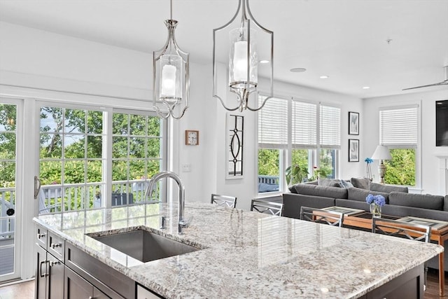 kitchen with light stone countertops, sink, a notable chandelier, wood-type flooring, and decorative light fixtures