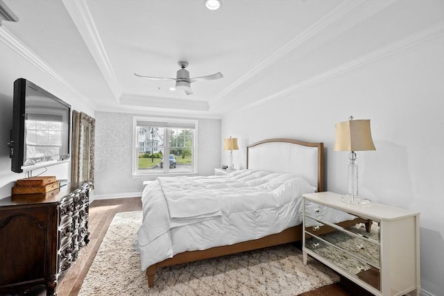 bedroom with wood-type flooring, a raised ceiling, ceiling fan, and ornamental molding