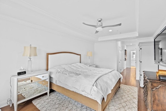 bedroom featuring a tray ceiling, ceiling fan, hardwood / wood-style floors, and ornamental molding