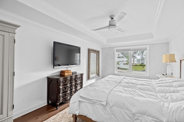 bedroom with wood-type flooring, a raised ceiling, ceiling fan, and ornamental molding