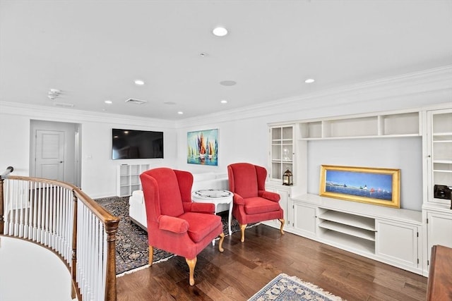 living area with built in shelves, dark hardwood / wood-style floors, and ornamental molding