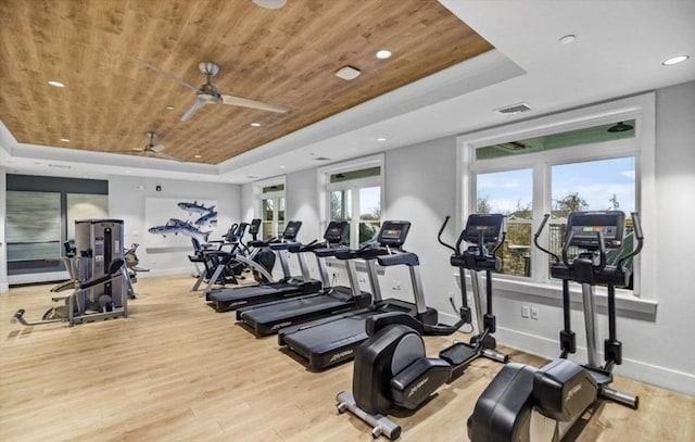 gym with a tray ceiling, light hardwood / wood-style flooring, ceiling fan, and wooden ceiling