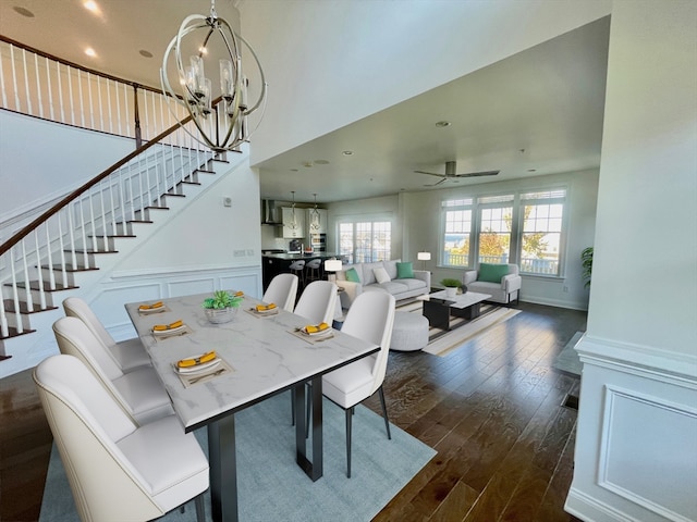 dining space featuring ceiling fan with notable chandelier and dark wood-type flooring