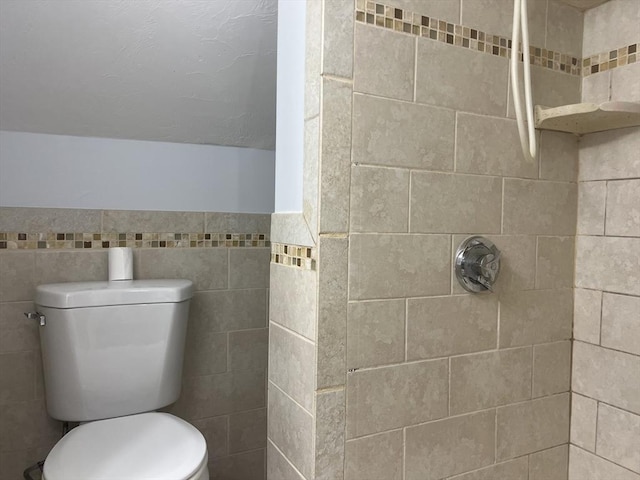 bathroom featuring tiled shower, lofted ceiling, toilet, and tile walls