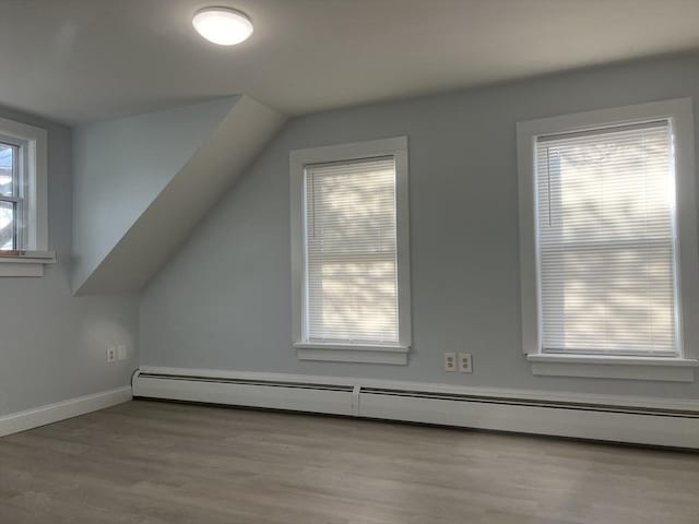 additional living space featuring lofted ceiling, light hardwood / wood-style flooring, and baseboard heating