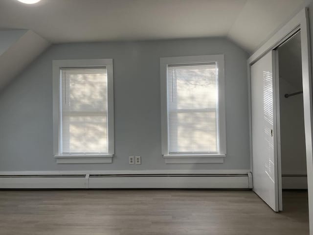 bonus room with light wood-type flooring, vaulted ceiling, and baseboard heating