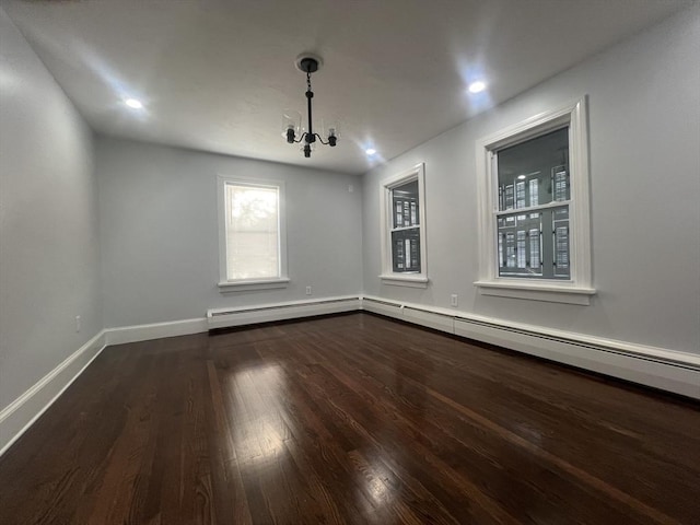 empty room with hardwood / wood-style flooring, a notable chandelier, and a baseboard heating unit