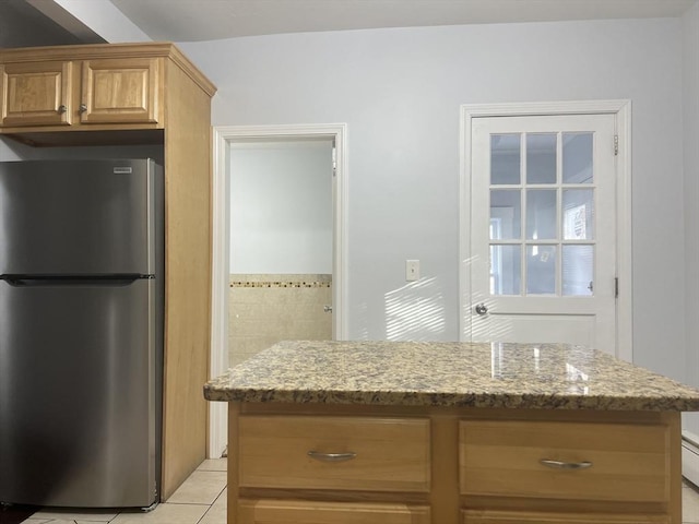 kitchen with light stone counters, stainless steel refrigerator, and light tile patterned flooring