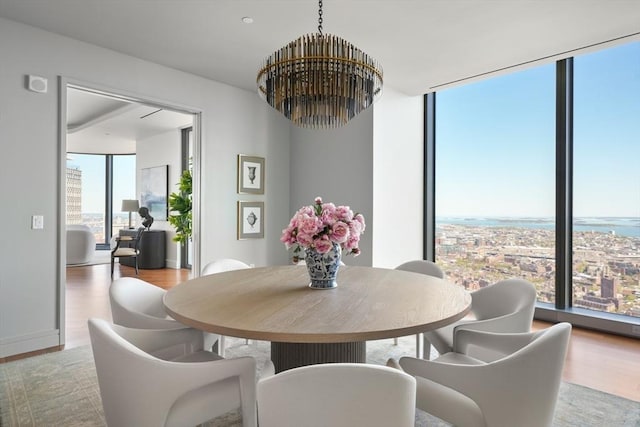 dining room featuring an inviting chandelier, floor to ceiling windows, and wood finished floors