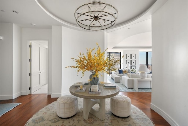 corridor with wood finished floors, baseboards, and a notable chandelier