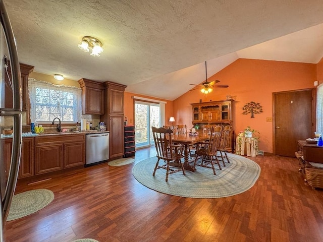 dining space featuring sink, a textured ceiling, dark hardwood / wood-style flooring, and vaulted ceiling