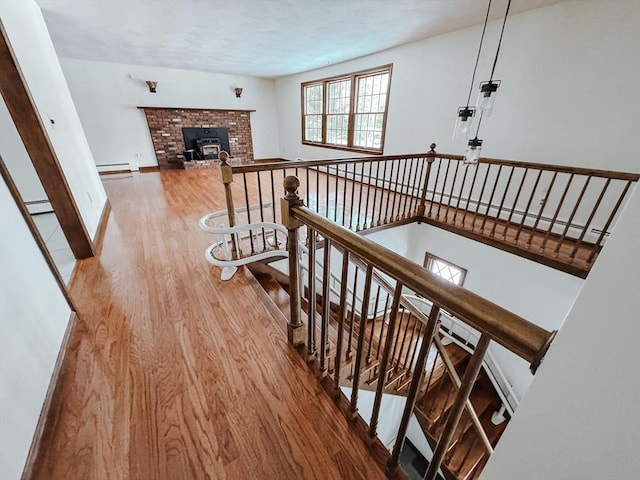 staircase featuring a baseboard heating unit, a baseboard radiator, baseboards, and wood finished floors