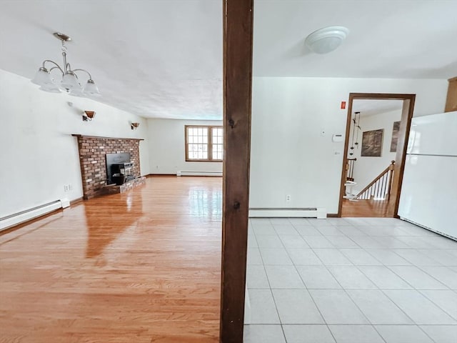 unfurnished living room with a chandelier, light wood-style flooring, and baseboard heating