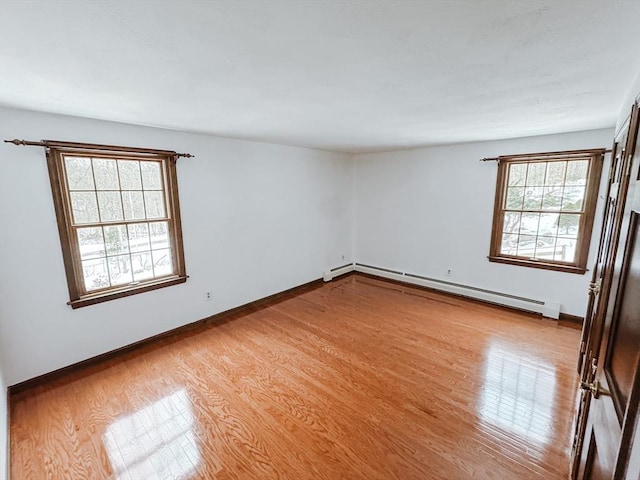 empty room featuring baseboards, light wood finished floors, and baseboard heating