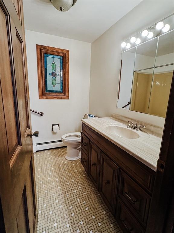 bathroom with toilet, tile patterned floors, baseboard heating, and vanity