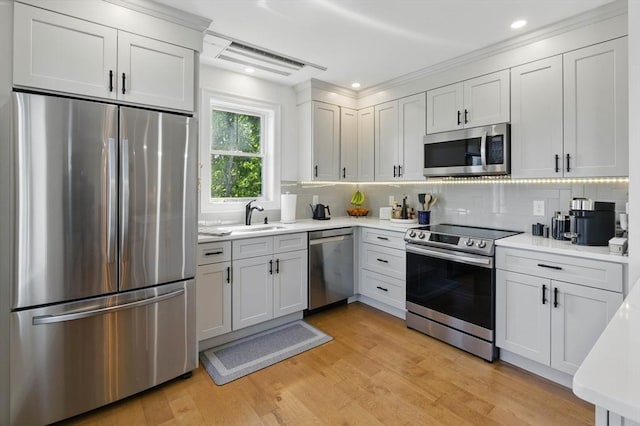 9 Boston St Unit 3, Salem, MA 01970 - kitchen with appliances with stainless steel finishes, a sink, light countertops, backsplash, and light wood-style flooring