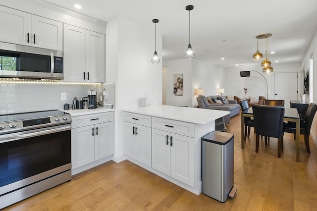 9 Boston St Unit 3, Salem, MA 01970 - kitchen with stainless steel appliances, a peninsula, backsplash, light countertops, and light wood-style flooring
