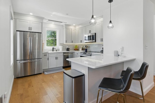 9 Boston St Unit 3, Salem, MA 01970 - kitchen featuring appliances with stainless steel finishes, a peninsula, a breakfast bar area, light wood finished floors, and recessed lighting