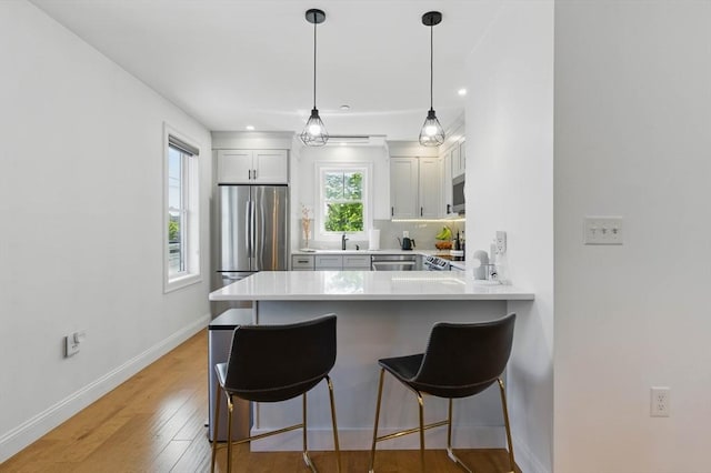 9 Boston St Unit 3, Salem, MA 01970 - kitchen featuring stainless steel appliances, a sink, a breakfast bar, light countertops, and a peninsula