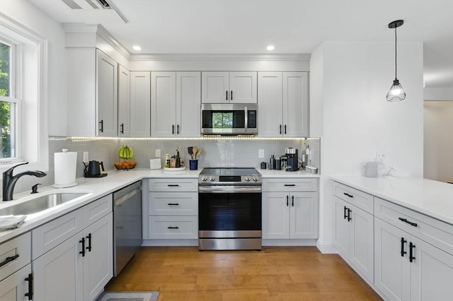 9 Boston St Unit 3, Salem, MA 01970 - kitchen featuring appliances with stainless steel finishes, light wood-style floors, backsplash, a sink, and light countertops