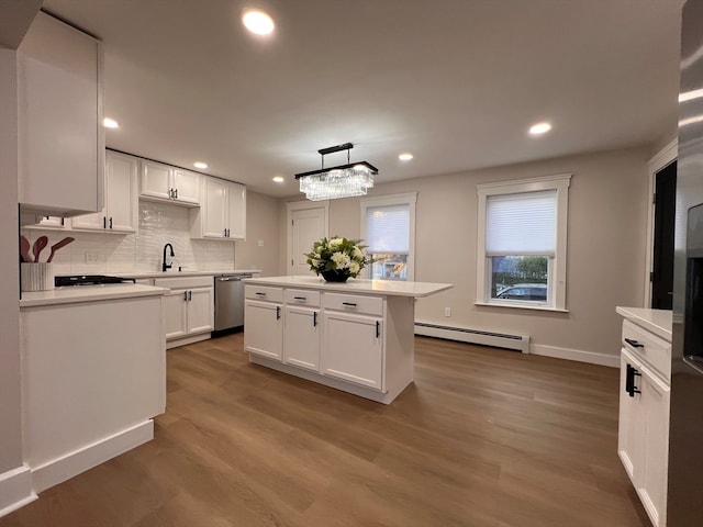 kitchen featuring white cabinetry, dishwasher, hanging light fixtures, and a baseboard radiator