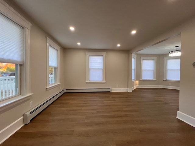 unfurnished room featuring an inviting chandelier, a baseboard heating unit, and dark wood-type flooring