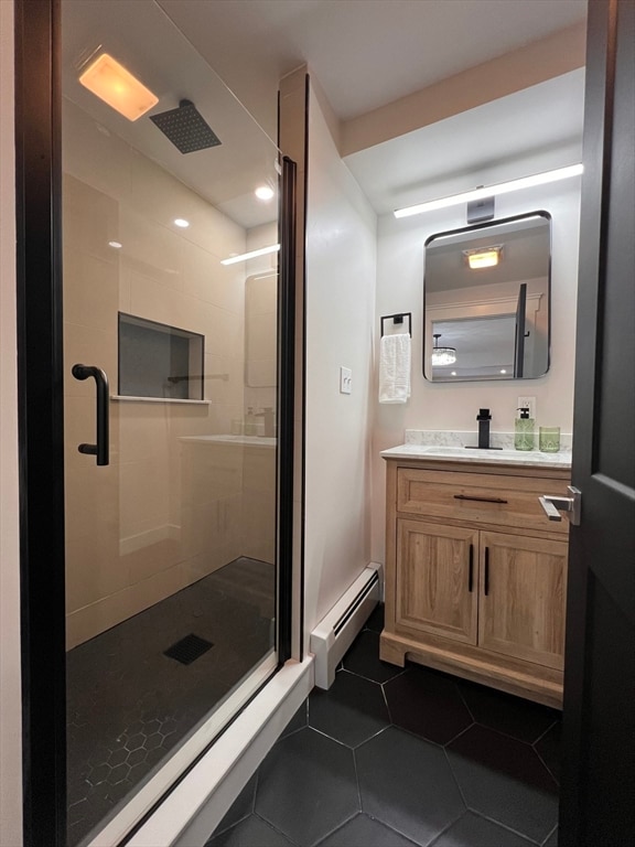 bathroom with a shower with door, vanity, a baseboard heating unit, and tile patterned flooring