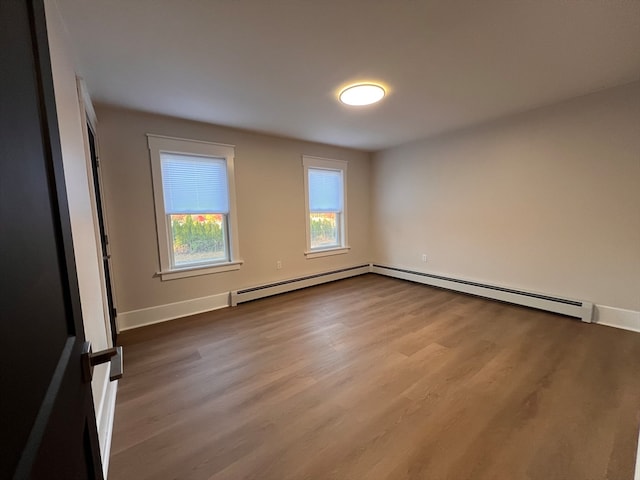 unfurnished room with baseboard heating and hardwood / wood-style flooring